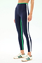Someone wears SPLITS59 Sam High Waist Rigor 7/8 leggings in Indigo/Spearmint, featuring green and white side stripes, paired with white sneakers with green accents, standing against a light background.