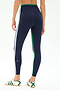 A person is shown from the back wearing SPLITS59 Sam High Waist Rigor 7/8 leggings in Indigo/Spearmint with white and green side stripes, paired with white sneakers featuring green accents.