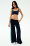 Model in SPLITS59 Heritage Velour Pant in Indigo/Grass, featuring soft navy velour with green stripes and a modern ankle-length wide leg, poses against a plain white background.