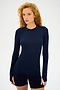 A curly-haired person stands against a plain background wearing the super soft Louise Rib Long Sleeve in Indigo from SPLITS59 and black shorts.