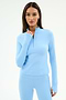 A woman wears the SPLITS59 Tess Rigor Half Zip Waist Length top in Skylight, a soft nylon-spandex blend, paired with matching leggings, standing against a plain white background.