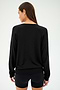 Individual wearing a stylish SPLITS59 Bennie Fleece V-Neck Sweatshirt in black and shorts, facing away.