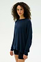A person with curly hair wears the SPLITS59 Andie Fleece Sweatshirt in Indigo and black shorts, standing against a plain light background.
