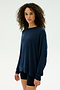 A person with curly hair wears the SPLITS59 Andie Fleece Sweatshirt in Indigo and black shorts, standing against a plain light background.