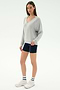 A woman wears the SPLITS59 Bennie Fleece V Neck Sweatshirt in Heather Grey/White with navy bike shorts, striped white socks, and white sneakers against a plain background. This cozy sweatshirt is made in Los Angeles.