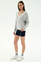 A woman wears the SPLITS59 Bennie Fleece V Neck Sweatshirt in Heather Grey/White with navy bike shorts, striped white socks, and white sneakers against a plain background. This cozy sweatshirt is made in Los Angeles.