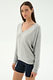 A woman in the SPLITS59 Bennie Fleece V Neck Sweatshirt in Heather Grey/White, made in Los Angeles, stands against a plain white background wearing black shorts.