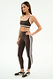 A woman wears the SPLITS59 Bianca High Waist Rigor 7/8 leggings in Dark Chocolate/White, featuring white side stripes and performance fabric, paired with a matching sports bra and black-and-white sneakers.
