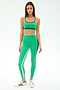 A woman faces forward on a plain white background, wearing the SPLITS59 Eva Rigor Double Strap Bra in Spearmint/Indigo and matching leggings, paired with white sneakers with green stripes.