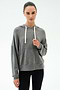 A woman wears the SPLITS59 Joey Long Sleeve Hoodie in Medium Heather Grey and black spandex leggings, standing against a plain light background.