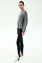 A person stands against a plain background wearing the SPLITS59 Joey Long Sleeve Hoodie in Medium Heather Grey, black spandex leggings, and white sneakers with black details.