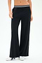 A person wears SPLITS59 Michele Airweight Trouser - Black, featuring a wide-leg fit and a white-and-black striped waistband, paired with white sneakers against a plain background.
