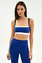 A woman wears the SPLITS59 Monah Rigor Bra in Cobalt/Black with matching high-waisted leggings, standing against a plain white background.