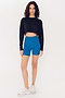 A woman in a SPLITS59 Noah Fleece Crop Sweatshirt - Black and blue bike shorts standing against a white background.