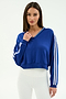 A woman models the SPLITS59 Ellie Fleece V Neck Sweatshirt in Cobalt/White, featuring white sleeve stripes, paired with white ribbed leggings against a plain background for an athletic look.