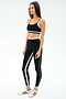 A woman wears the SPLITS59 Sam High Waist Rigor 7/8 leggings in Black/Military with white and green stripes and a matching sports bra, paired with white sneakers with green accents, standing against a plain light background.