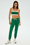 A person stands wearing a green SPLITS59 Sonja Fleece Sweatpant paired with a matching sports bra and white sneakers, against a plain background.