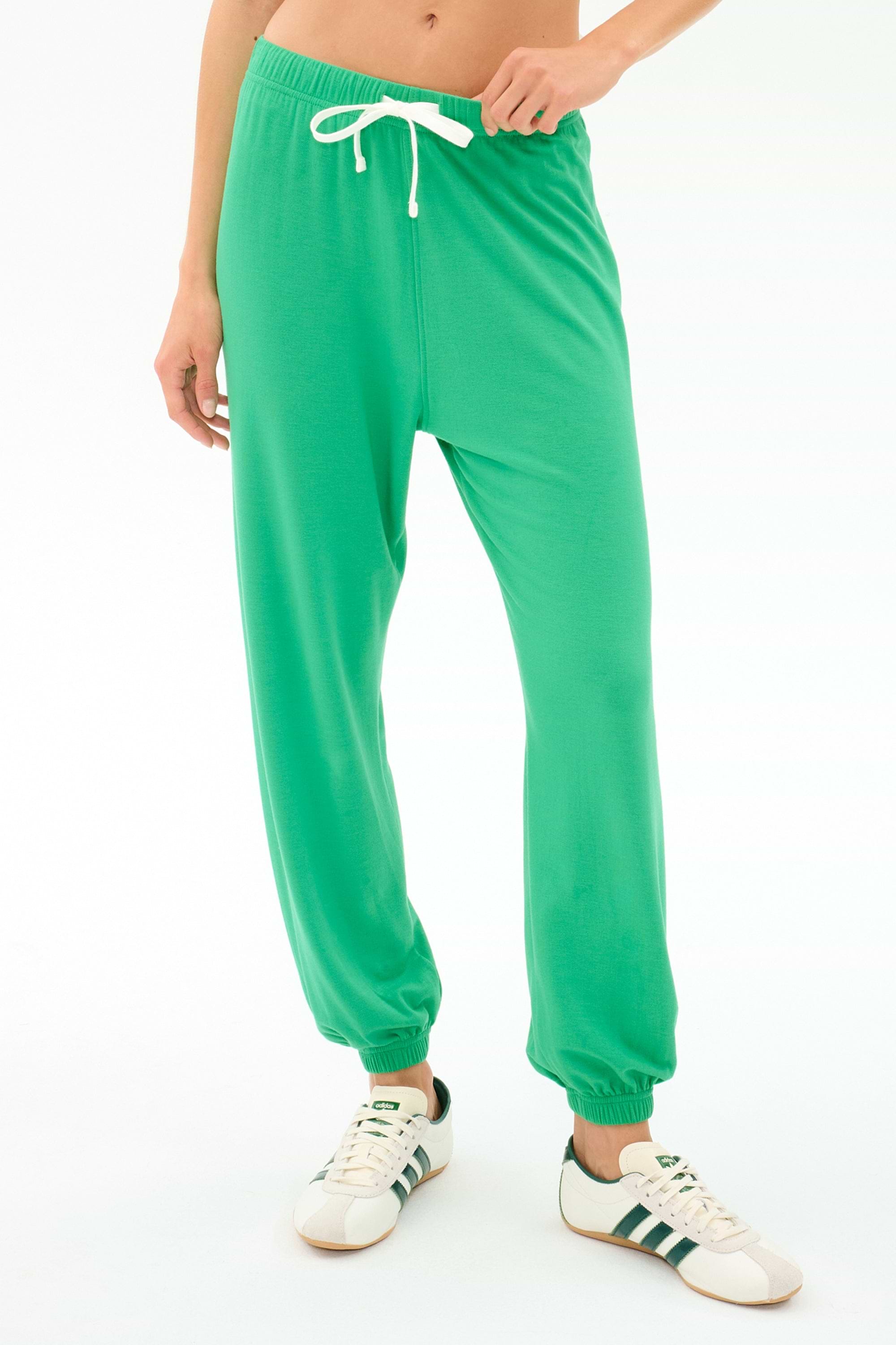 A person wears the SPLITS59 Andie Oversized Fleece Sweatpant in Spearmint, featuring a white drawstring, paired with white sneakers with green stripes—ideal for cool weather workouts—standing against a plain white background.