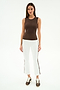 A woman stands against a white background wearing a sleeveless brown top, brown sneakers, and SPLITS59 Raquel High Waist Supplex Crop leggings in White/Dark Chocolate.