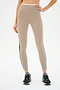 A person wearing SPLITS59 Sam High Waist Rigor 7/8 leggings in Latte/Black with black sneakers, standing against a white background.