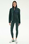 A woman wears the SPLITS59 Harris Sherpa Jacket in Military/Indigo, paired with dark green leggings and white sneakers, standing against a plain light background.