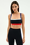 A woman models the SPLITS59 Monah Rigor Bra in Black/Cobalt with matching high-waisted leggings, standing against a plain, light background.