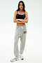 A woman stands with arms crossed, wearing a black crop top and SPLITS59 Andie Oversized Fleece Varsity 59 Sweatpant in Heather Grey with "59" on the left thigh—ideal for cool weather workouts—paired with white sneakers against a light background.