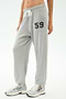 Model wears SPLITS59 Andie Oversized Fleece Varsity 59 Sweatpant in Heather Grey with a "59" graphic on the left thigh and white sneakers—ideal for cool weather workouts, posed against a plain background.