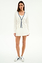 A woman faces forward against a plain white background, wearing the SPLITS59 Bekah Knit Cardigan in White/Indigo with blue trim, paired with a white pleated skirt and nylon athletic sneakers.