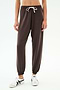 A person wears SPLITS59's Andie Oversized Fleece Sweatpant in Dark Chocolate with a white drawstring and white sneakers, standing against a plain white background. These ultra luxe fleece sweatpants are made in Los Angeles.