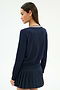A woman with long brown hair, wearing the SPLITS59 Bekah Knit Cardigan in Indigo/White, stands turned slightly to the side against a plain light background.