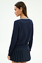 A woman with long brown hair, wearing the SPLITS59 Bekah Knit Cardigan in Indigo/White, stands turned slightly to the side against a plain light background.
