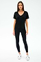 A woman faces forward, wearing the SPLITS59 Georgia Jersey V-Neck in black—crafted from soft viscose and spandex—with black leggings and white sneakers, set against a plain white background.