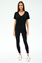 A woman faces forward, wearing the SPLITS59 Georgia Jersey V-Neck in black—crafted from soft viscose and spandex—with black leggings and white sneakers, set against a plain white background.