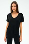 A woman faces forward, wearing the SPLITS59 Georgia Jersey V-Neck in black—crafted from a soft viscose-spandex blend—paired with black pants, set against a white background.