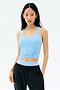 A woman wears the SPLITS59 Ashby Rib Tank in Skylight with black pants, standing against a white background—an ideal look for gym workouts.
