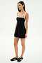 A woman poses against a plain background wearing the SPLITS59 Monah Rigor Dress in Black/White, styled with black Adidas sneakers featuring white stripes.