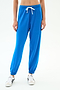 A person wears SPLITS59 Andie Oversized Fleece Sweatpant in Classic Blue with a white drawstring and sneakers, ideal for cool weather workouts, standing against a plain white background.