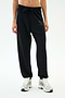 A person wears SPLITS59's Andie Oversized Fleece Varsity 59 Sweatpant in black, featuring a "59" on the left thigh, paired with white sneakers—ideal for cool weather workouts—standing against a plain white background.