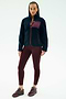 A person stands facing forward wearing the SPLITS59 Harris Sherpa Jacket in Indigo/Dark Cherry, paired with burgundy leggings and sneakers, against a plain white background.