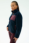 A woman stands against a plain background wearing the SPLITS59 Harris Sherpa Jacket in Indigo/Dark Cherry, featuring soft 100% polyester fleece with a maroon chest pocket and zipper, paired with maroon leggings.