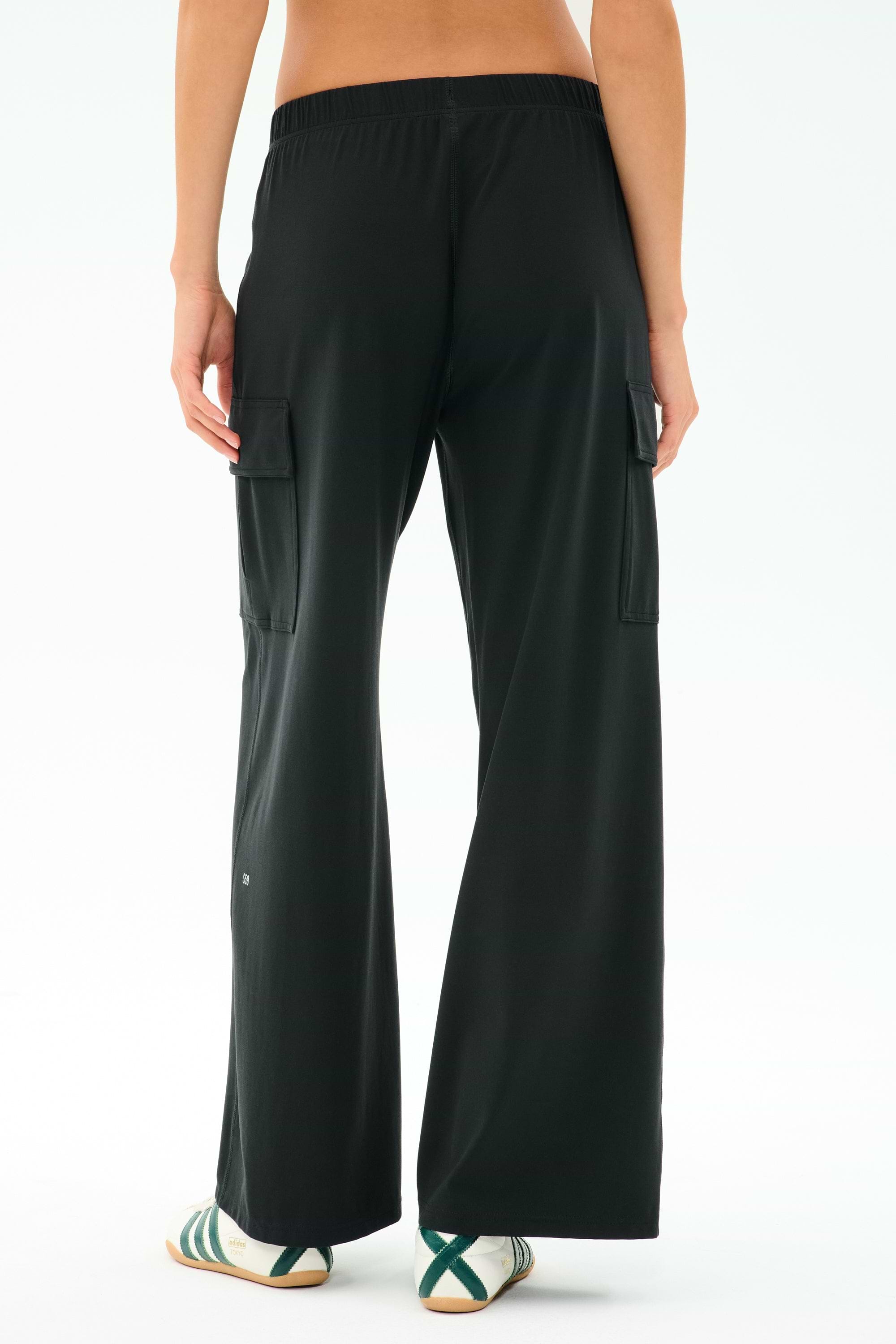 A person wearing SPLITS59 Alex Airweight Cargo Pant in black and white sneakers with green stripes, photographed from the back. Ideal for a post-workout stroll or a casual day out.