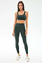 A woman faces forward wearing the SPLITS59 Airweight Rib High Waist 7/8 leggings in Military, paired with a matching sports bra and white sneakers against a plain white background.