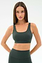 A woman with long brown hair wears the SPLITS59 Airweight Rib Bra in Military and matching high-waisted leggings, made from soft nylon spandex, standing with hands on hips against a plain white background.