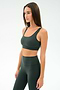 A woman wears the SPLITS59 Airweight Rib Bra in Military, paired with matching high-waisted leggings, both made from nylon spandex fabric, standing against a plain light background.