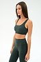 A woman wears the SPLITS59 Airweight Rib Bra in Military, paired with matching high-waisted leggings, both made from nylon spandex fabric, standing against a plain light background.