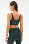 A woman wearing the SPLITS59 Airweight Rib Bra - Military stands facing away from the camera, paired with matching dark green high-waisted leggings made from soft nylon spandex against a plain background.
