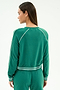 A woman with long straight hair and gold stud earrings wears the SPLITS59 Brooks Fleece Sweatshirt With Stripe in Arugula/White, featuring soft modal fabric and white stripes on the sleeves, cuffs, and waist.