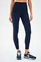 Someone in SPLITS59's Ella High Waist Airweight 7/8 leggings in Indigo/Black Currant and navy sneakers stands against a plain backdrop. The butter-soft fabric is perfect for hot yoga, though their head isn't visible.