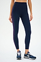 Someone in SPLITS59's Ella High Waist Airweight 7/8 leggings in Indigo/Black Currant and navy sneakers stands against a plain backdrop. The butter-soft fabric is perfect for hot yoga, though their head isn't visible.